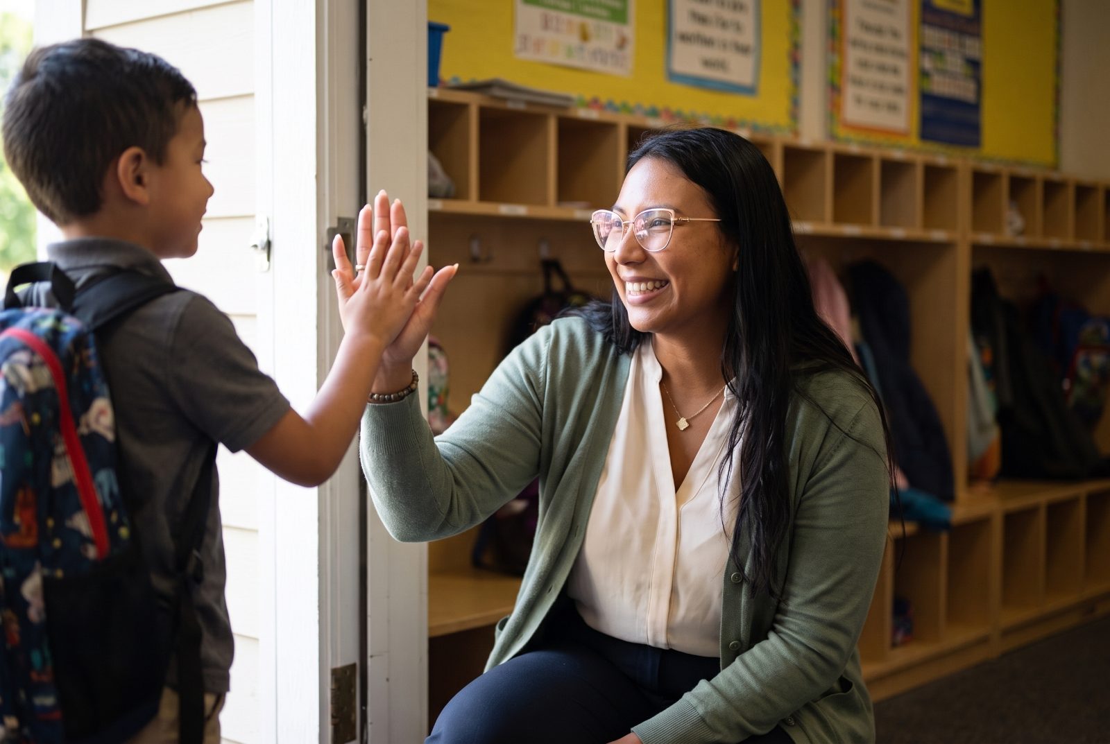 Janessa greeting a student with a high five at the classroom door